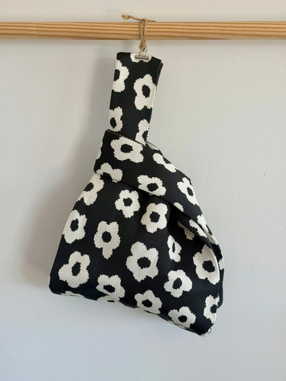 Black and white flower knit tote bag hanging on a wooden rod