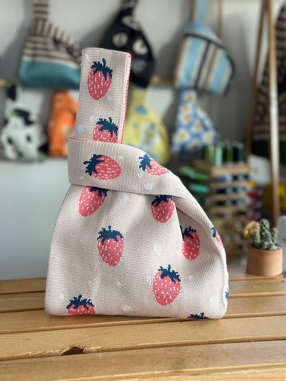 Small fabric bag with strawberry pattern on a wooden surface